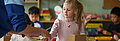 Girl in a pink T-shirt playing at a table.